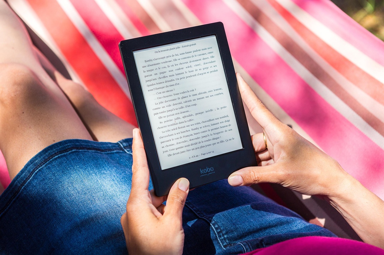 デジタル書籍を表示する電子書籍リーダーとノートパソコンが置かれたデスク